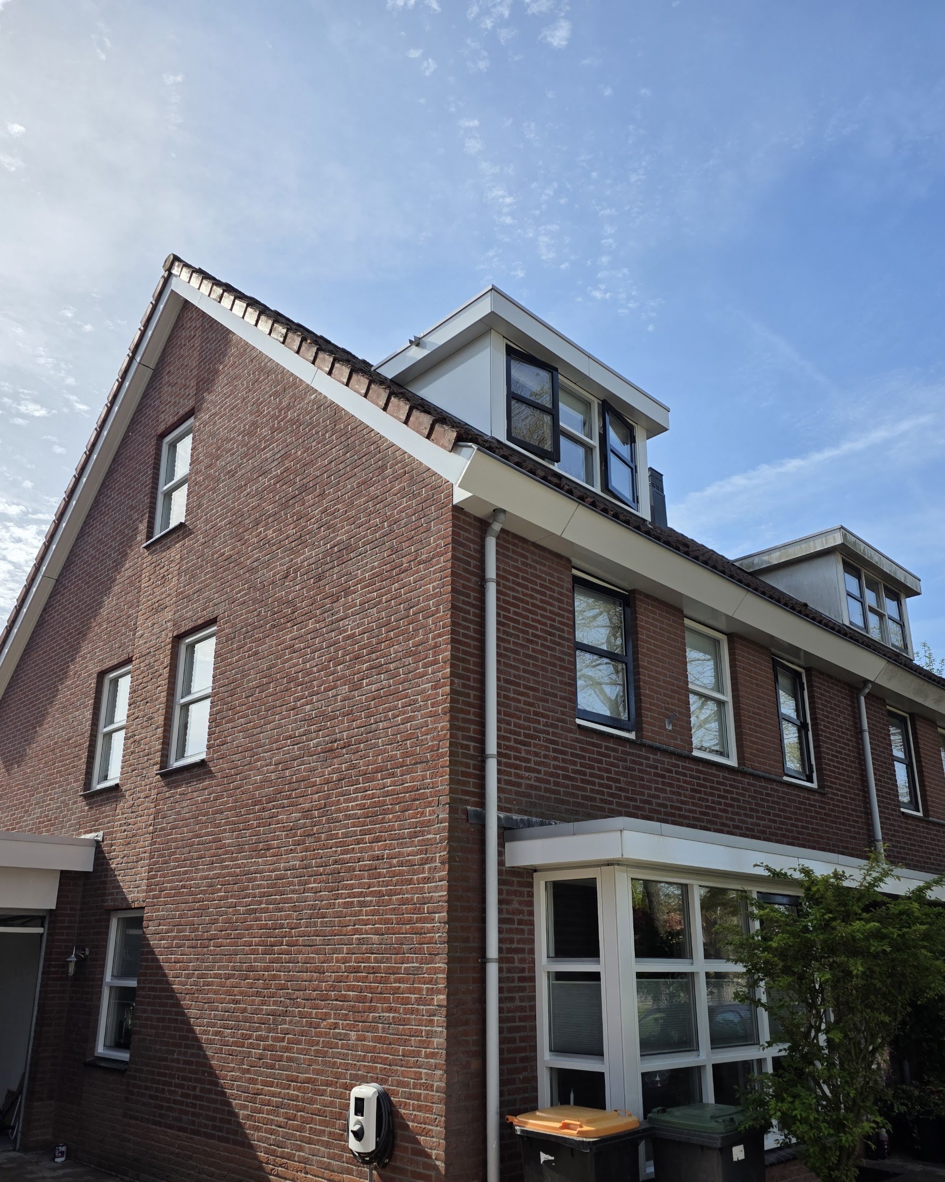 Bakstenen hoekhuis met wit geschilderde kozijnen en dakkapel