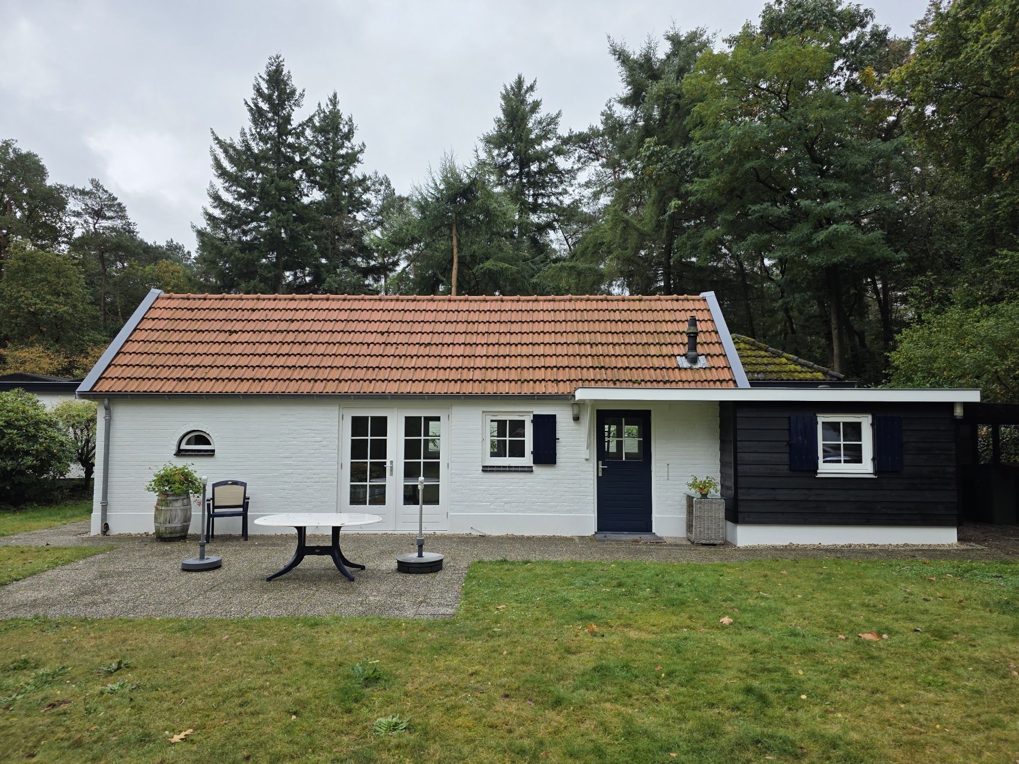 Wit geschilderd huisje met donkere aanbouw, net opgeleverd